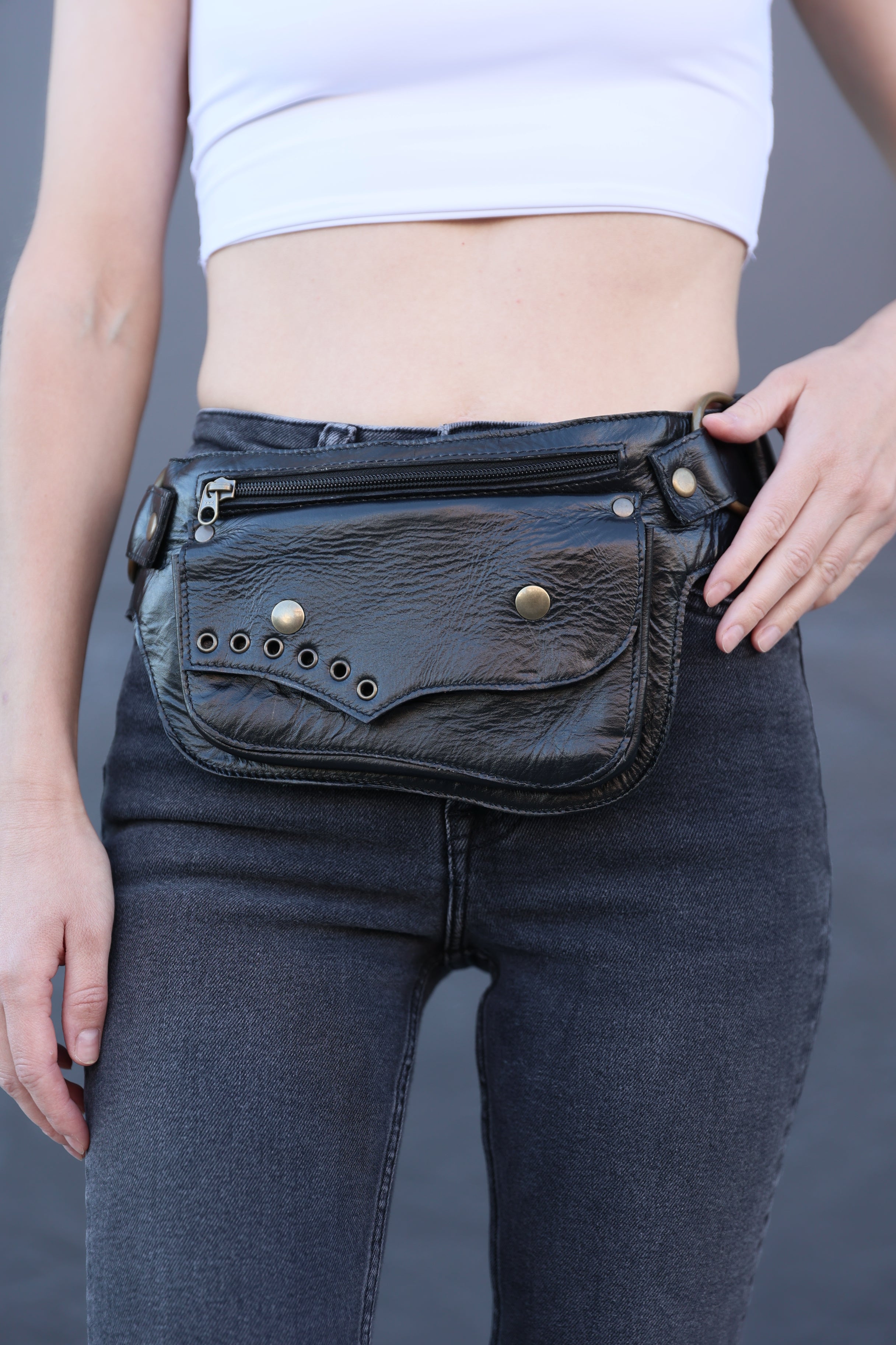 Close-up of black handmade leather festival belt bag worn by a woman