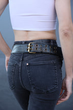 Person wearing dark jeans with a black belt on a gray background