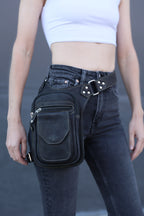 Person wearing a black leather motorcycle bag on their hip against a gray background