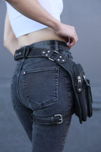 Person wearing black leather motorcycle pants with zippers on a gray background