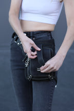 Person holding a black leather bag with a blurred background