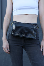 Person wearing black jeans with studded details on a gray background