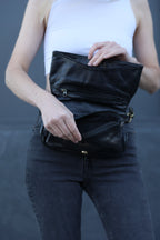 Person wearing a black leather jacket over a white shirt against a gray background