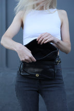 Person holding a black leather jacket against a gray background