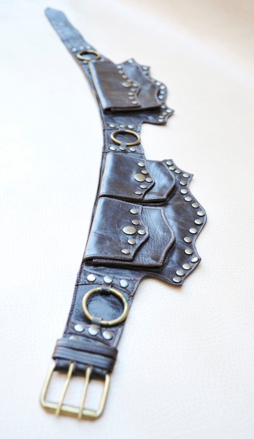 Brown leather belt laying on a beige background
