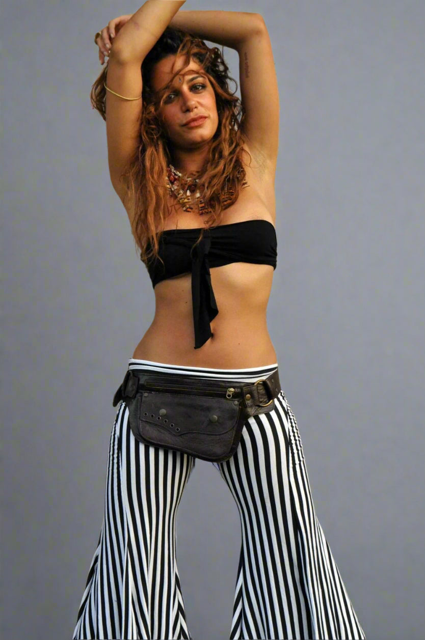 Woman wearing a black bikini top and striped pants with an Ellko leather waist bag against a gray background