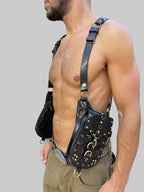 A person wearing a black leather holster with pockets and key rings, designed for carrying while traveling or at outdoor events.